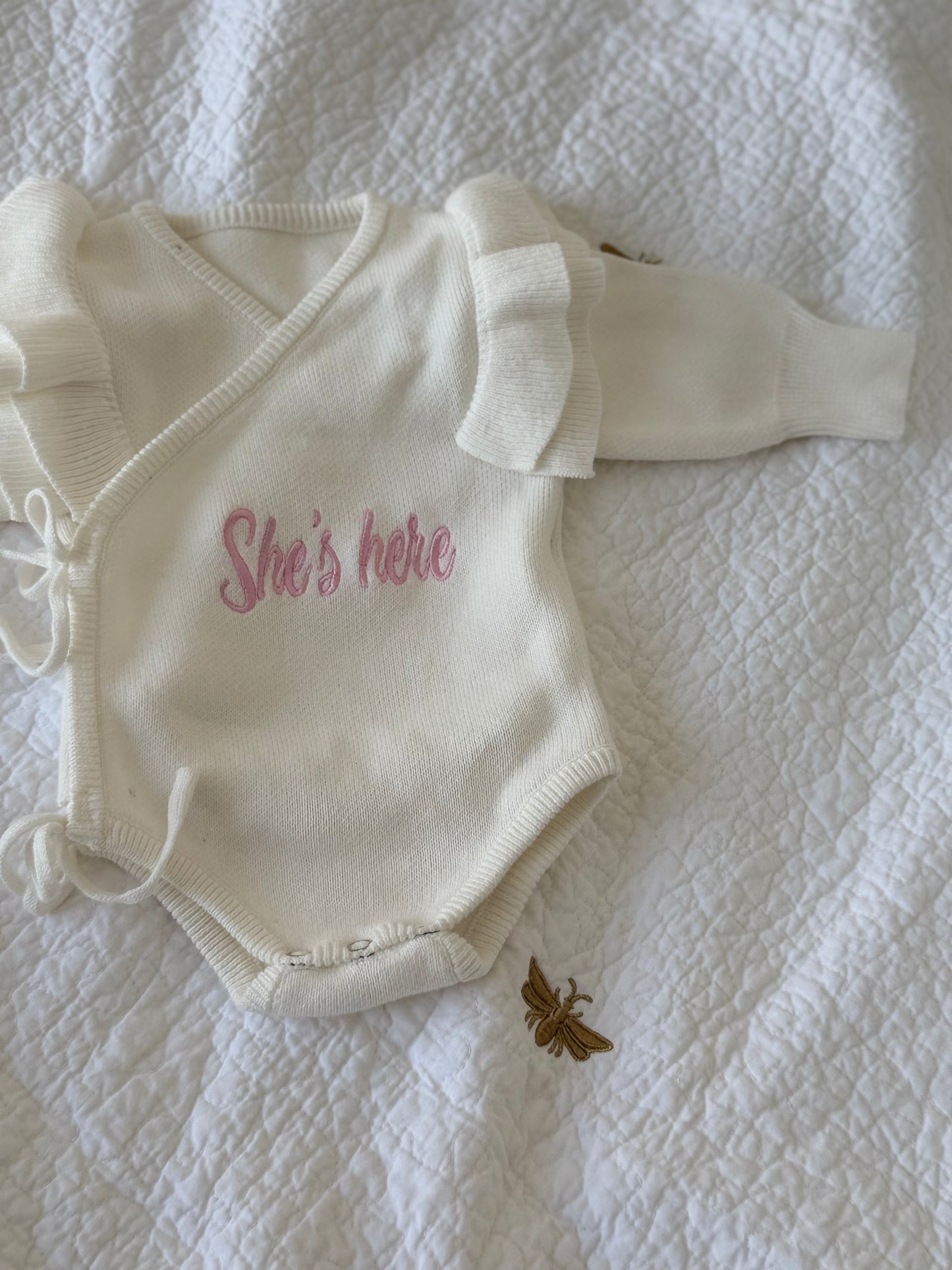 Personalised off-white organic cotton knit baby romper with "She's Here" embroidery — beautiful newborn arrival gift Dubai
