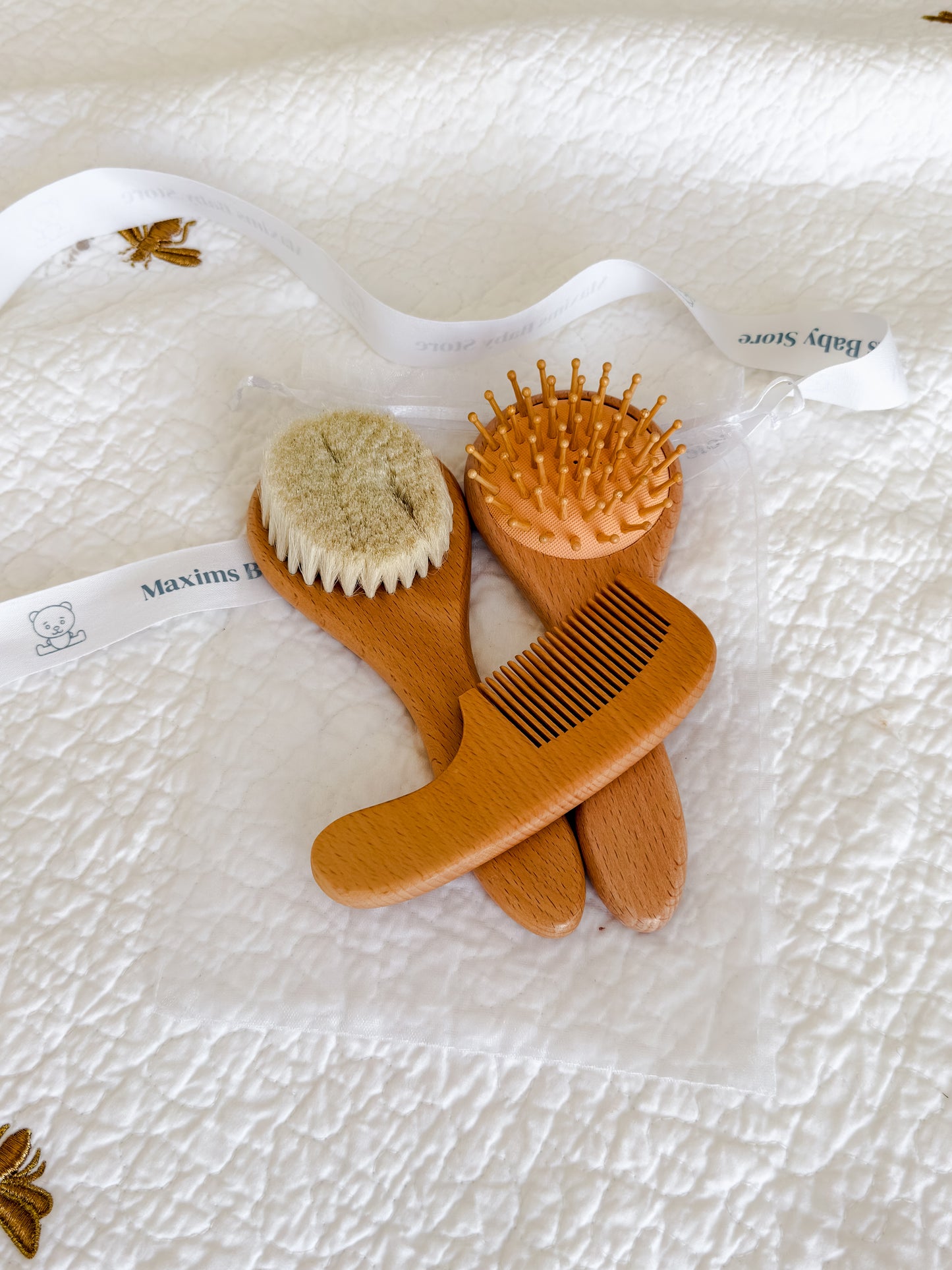 Natural beechwood baby brush set with goat hair bristles and wooden comb on cream textured background
