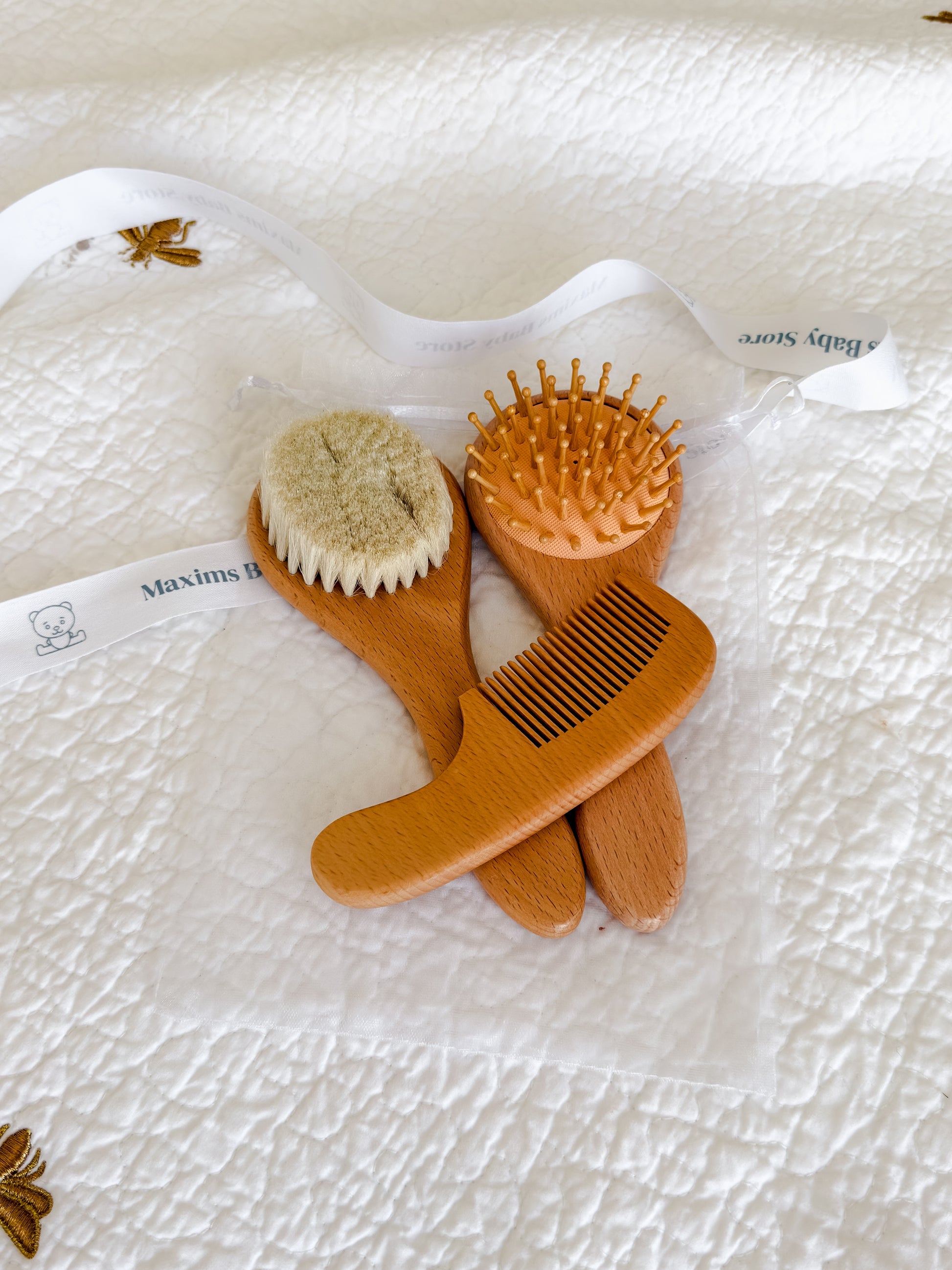 Natural beechwood baby brush set with goat hair bristles and wooden comb on cream textured background
